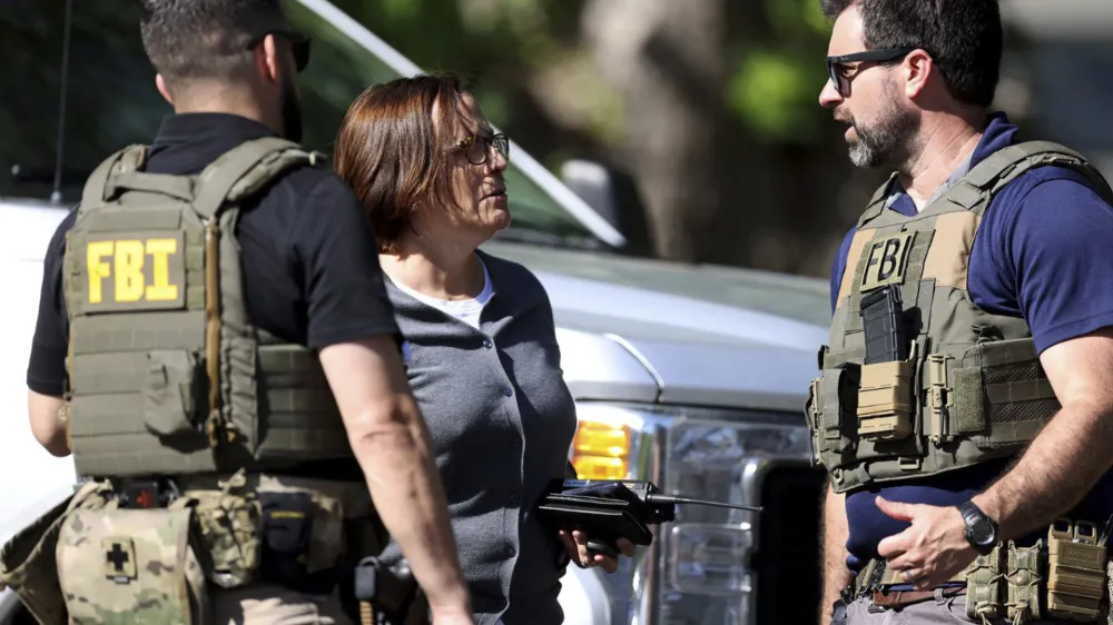 Members of FBI talk with each other at the scene of a shooting on Galway Drive in Charlotte, N.C., on Monday, April 29, 2024, Multiple law enforcement officers were shot while serving a warrant for a felon wanted for possessing a firearm. (Khadejeh Nikouyeh/The Charlotte Observer via AP)