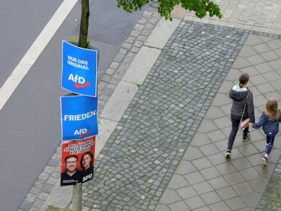 People walk past a tree with placards of SPD and AfD parties on the day of a protest for democracy and against violence on Matthias Ecke, a member of the European Parliament, in Dresden, Germany, May 5, 2024. REUTERS/Matthias Rietschel