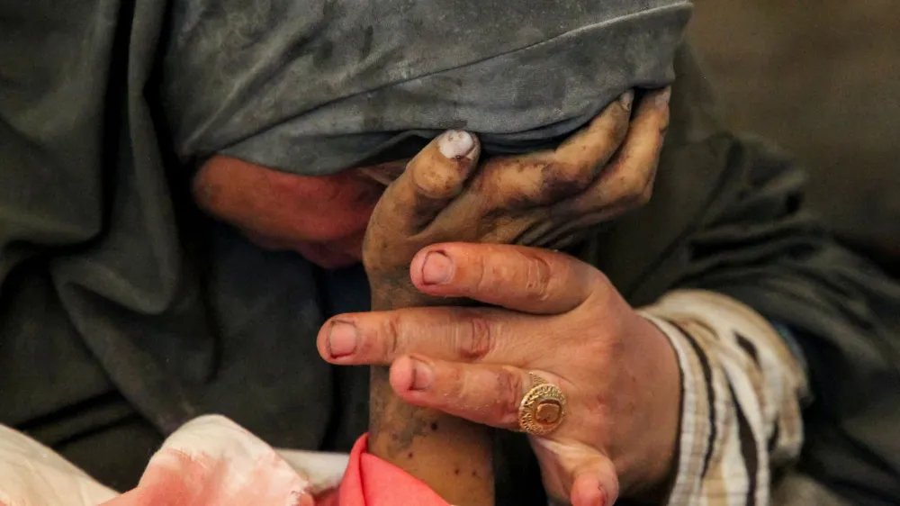 Palestinian woman Buthayna Abu Jazar reacts as she holds the hand of her son Hazma, who was killed in an Israeli strike, amid the ongoing conflict between Israel and Hamas, in Rafah, in the southern Gaza Strip May 9, 2024. REUTERS/Hatem Khaled