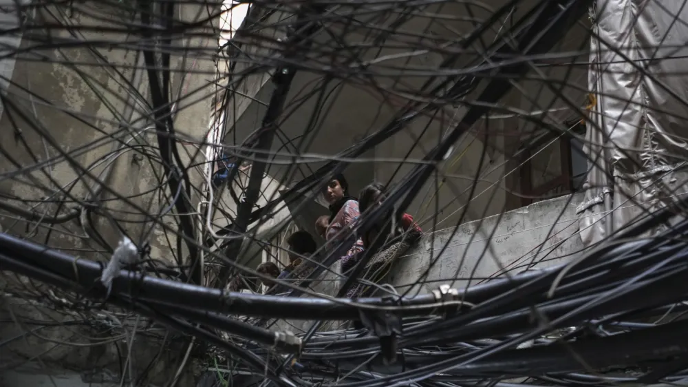 Palestinians watch from their apartment balcony a protest called by Palestinian Islamic Jihad movement, in solidarity with the Palestinian people in Gaza, at the Palestinian refugee camp of Chatila in Beirut, Lebanon, Saturday, May 11, 2023. The Arabic on his headband reads: "No God but Allah and Muhammed is his messenger, top, Al-Quds Brigades, center, and The Islamic Jihad group in Palestine." (AP Photo/Hassan Ammar)