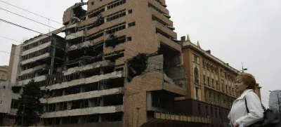 FILE- A woman walks in front of the destroyed former Serbian army headquarters in Belgrade, Serbia, March 24, 2010. Opposition groups in Serbia are planning protests against a real estate development project that will be financed by the firm of Donald Trump's son-in-law, Jared Kushner, at the site of the former Serbian army headquarters destroyed in a U.S.-led NATO bombing campaign in 1999. The Serbian government earlier this week signed a deal with a Kushner-related company for the 99-year lease of land in central Belgrade for the "revitalization" of the bombed-out buildings. (AP Photo/Darko Vojinovic, File)