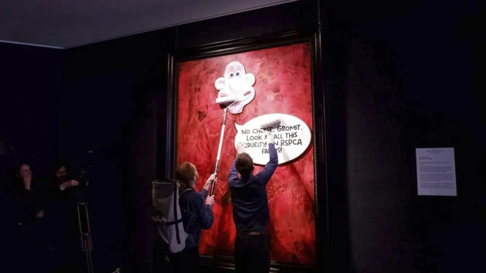 This photo released by Animal Rising shows activists pasting a picture of a character called Wallace, from the "Wallace and Gromit" comedy series, over a portrait of Britain's King Charles III at the Philip Mould Gallery in London, Tuesday June 11, 2024. Animal rights activists pasted a cartoon image over a portrait of King Charles III on Tuesday at a London art gallery, the latest in a series of incidents at U.K. museums as campaigners use vandalism to publicize their causes. (Animal Rising via AP)