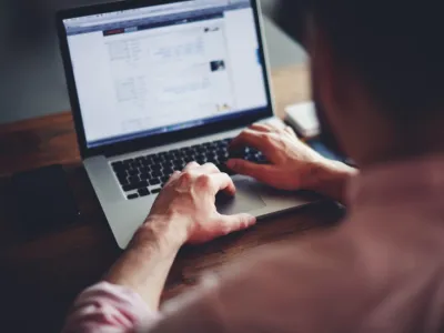Cropped image of a young man working on his laptop in a coffee shop, rear view of business man hands busy using laptop at office desk, young male student typing on computer sitting at wooden table