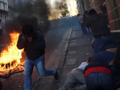 People cover their faces while demonstrators face members of Bolivia's military, as Bolivia's President Luis Arce "denounced the irregular mobilization" of some units of the country's army, in La Paz, Bolivia, June 26, 2024. REUTERS/Claudia Morales