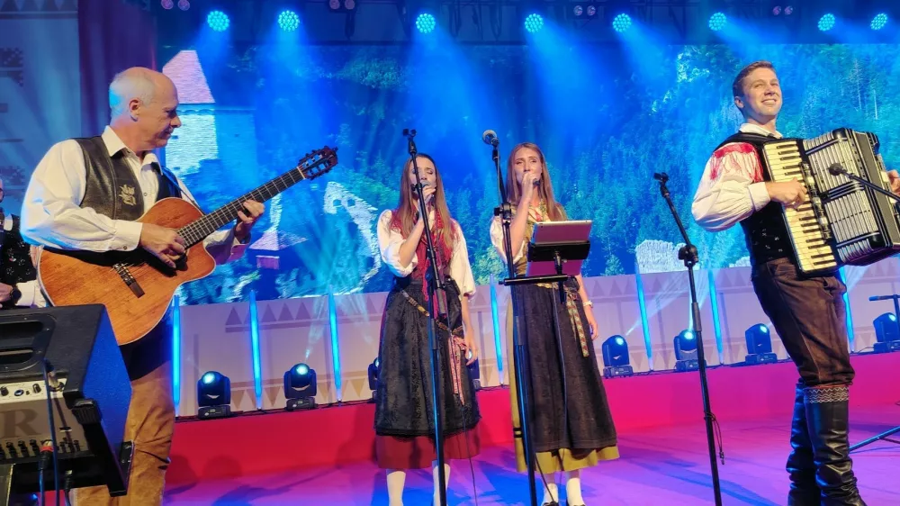 Ansambel Saša Avsenika na odru festivala z gostoma Gregorjem Avsenikom na kitari in Moniko Avsenik za mikrofonom. / Foto: Mojca Marot