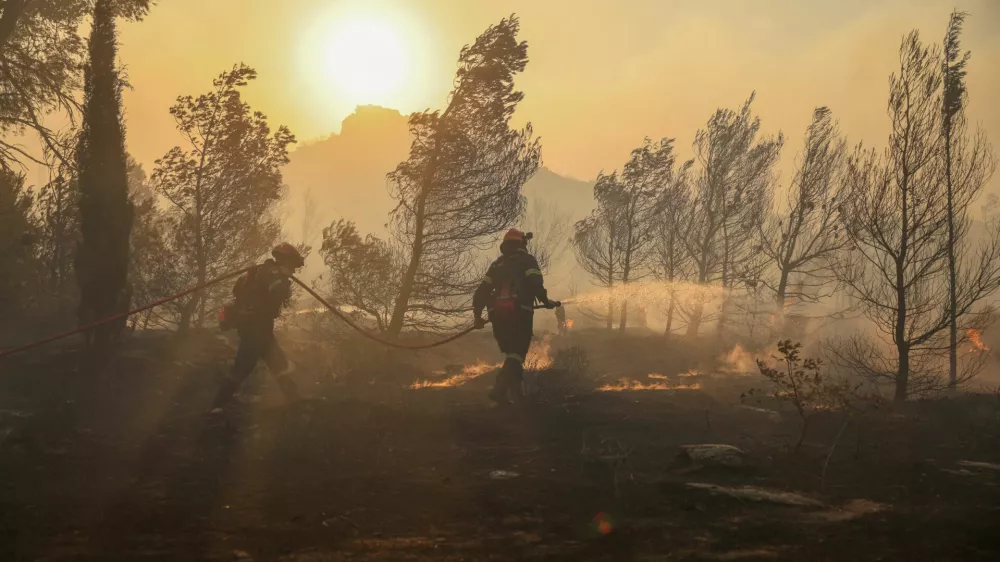 Firefighters try to extinguish a wildfire burning in Penteli, Greece, August 12, 2024. REUTERS/Stelios Misinas
