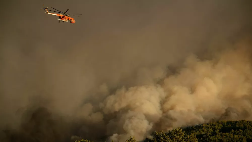 A firefighting helicopter flies over smoke rising from a wildfire burning in the village of Varnavas, near Athens, Greece, August 11, 2024. REUTERS/Hilary Swift