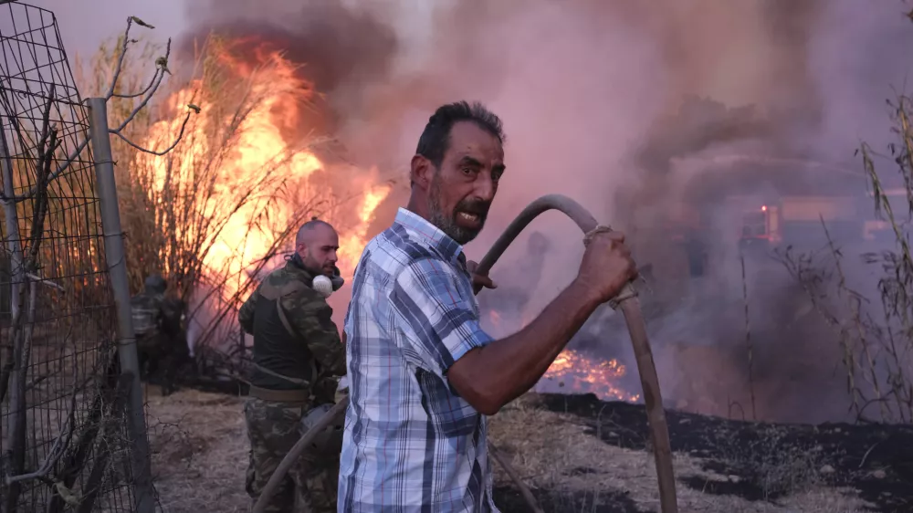 Volunteers try to extinguish the fire in northern Athens, Monday, Aug. 12, 2024, as hundreds of firefighters tackle a major wildfire raging out of control on fringes of Greek capital. (AP Photo/Aggelos Barai)