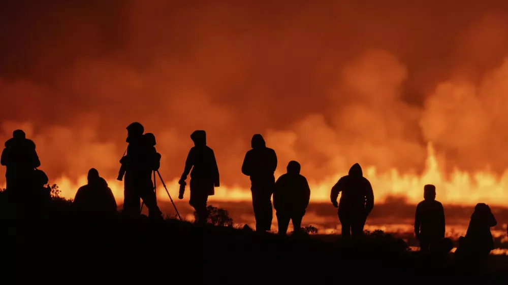 Tourists and visitors try to get a view of the eruption from a distance from the intersection between Reykjanesbraut, Iceland, and the road to Grindavik, Thursday, Aug. 22, 2024. (AP Photo/Marco di Marco)