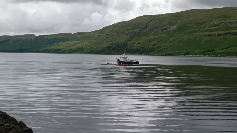 Igra deklice s kužkom na obrežju jezera Harport na &scaron;kotskem otoku Isle of Skye