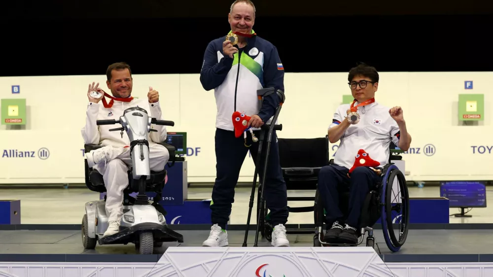 Paris 2024 Paralympics - Shooting - R4 - Mixed 10m Air Rifle Standing SH2 Final - Chateauroux Shooting Centre, Deols, France - August 30, 2024 Gold medallist Francek Gorazd Tirsek of Slovenia celebrates on the podium after the final with silver medallist Tanguy de La Forest of France and bronze medallist Huntae Seo of South Korea REUTERS/Eng Chin An