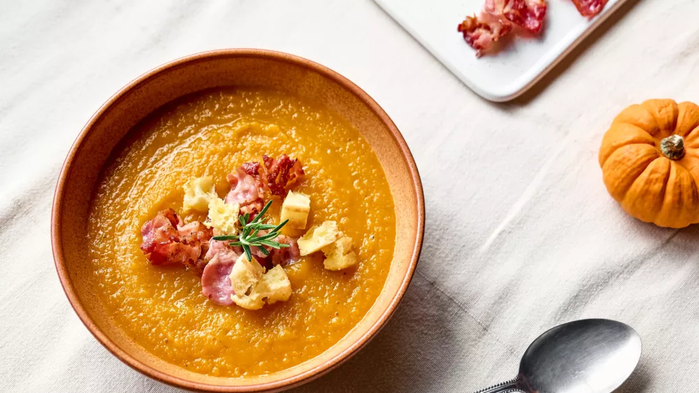 Pumpkin cream soup with roasted bacon and croutons in clay plate on the table with linen tablecloth. Autumn vegetable creamy soup puree. Healthy seasonal eating. / Foto: Ekaterina Fedulyeva