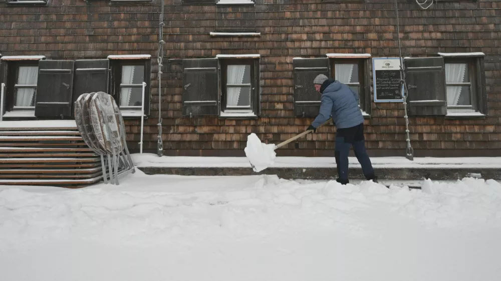 A worker clears snow in front of the "Muenchner Haus" mountain hut near the Zugspitze summit near Garmisch-Partenkirchen, Germany, September 12, 2024. REUTERS/Angelika Warmuth