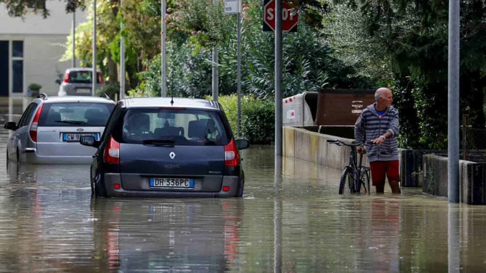 A man holds a bicycle as he stands in a flooded street, as the Emilia-Romagna region experiences floods triggered by severe weather, in Lugo, Emilia-Romagna, Italy, September 20, 2024. REUTERS/Ciro de Luca