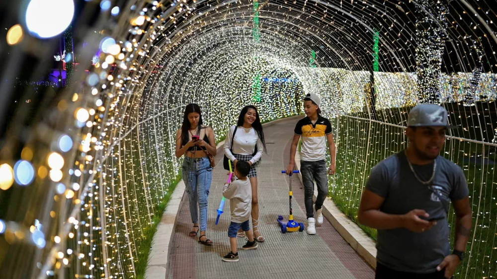 People walk through a tunnel made of Christmas lights in a public square, as the Christmas season kicks off as per a decree of Venezuela's President Nicolas Maduro, in Caracas, Venezuela October 1, 2024. REUTERS/Gaby Oraa