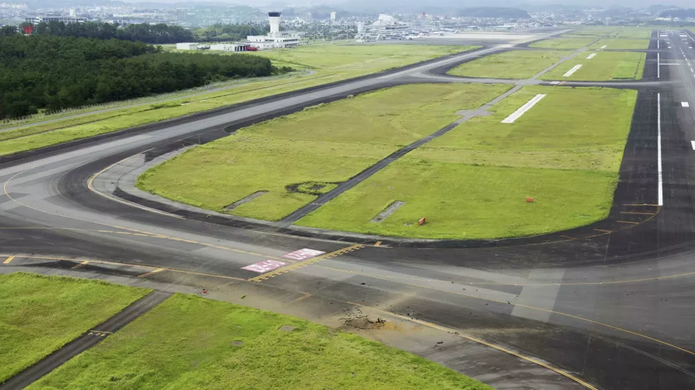 This photo taken from a Kyodo News helicopter shows part of a damaged taxiway, front, at Miyazaki Airport in southwestern Japan, Wednesday, Oct. 2, 2024, after an explosion was reported. (Kyodo News via AP)