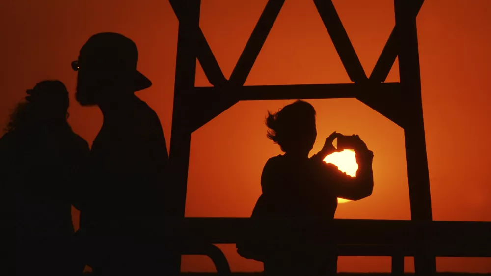 People enjoy a fall sunset along Lake Michigan and the North Pier, Sunday, Oct. 6, 2024, in St. Joseph, Mich. (Don Campbell/The Herald-Palladium via AP)