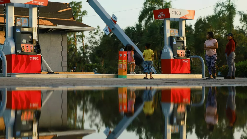 People stand near a bent structure at a gas station, after Hurricane Milton made landfall, in Lakewood Park, near Fort Pierce, in St. Lucie County, Florida, U.S., October 10, 2024. REUTERS/Jose Luis Gonzalez
