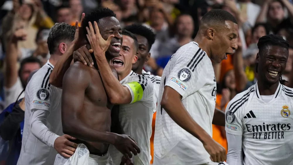 Real Madrid's Vinicius Junior, left, celebrates with teammates after scoring his side's fourth goal during the Champions League opening phase soccer match between Real Madrid and Borussia Dortmund at the Santiago Bernabeu stadium in Madrid, Tuesday, Oct. 22, 2024. Real Madrid won 5-2. (AP Photo/Manu Fernandez)