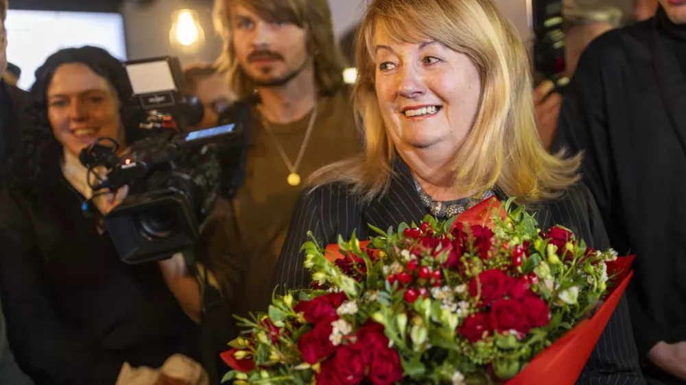 Leader of the Social Democratic Party Vilija Blinkeviciute, center, smiles as she waits for the results of the second round of Lithuania's parliamentary election, in an office in Vilnius, Lithuania, Sunday, Oct. 27, 2024. (AP Photo/Mindaugas Kulbis)