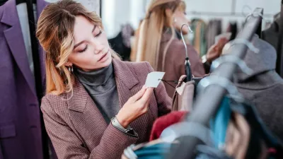 Check price. Elegant fashionable businesswoman shopping on weekend checking the price of dress / Foto: Yacobchuk