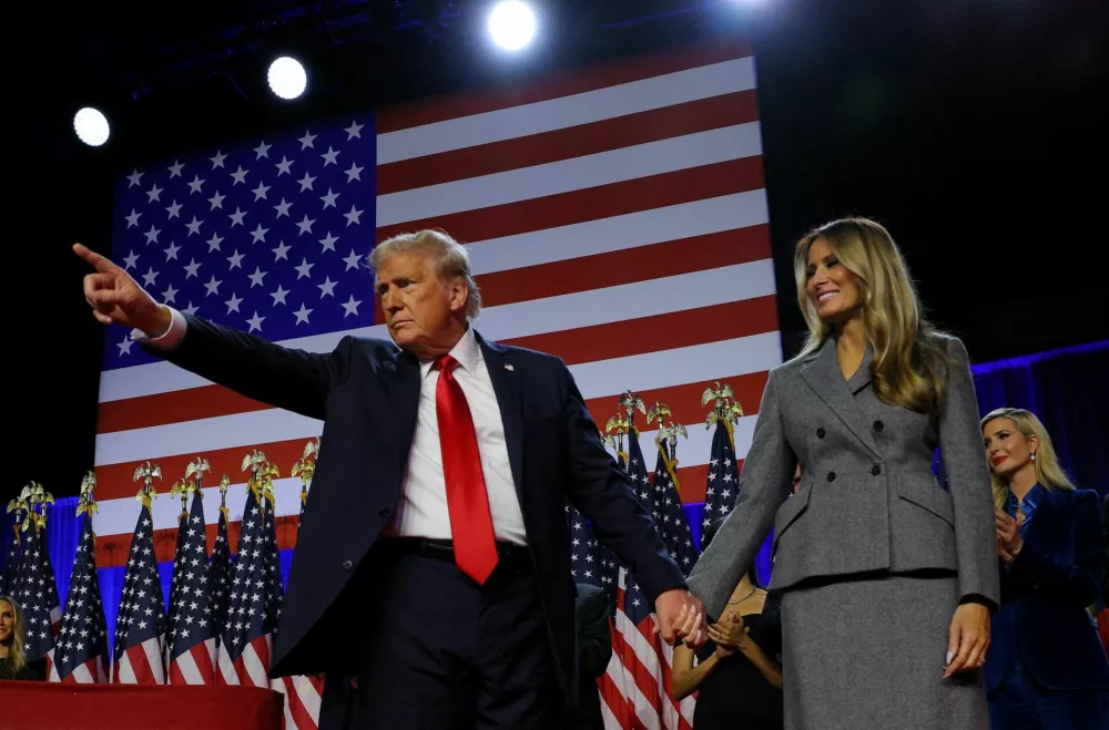 Republican presidential nominee and former U.S. President Donald Trump gestures as he holds hands with his wife Melania during his rally, at the Palm Beach County Convention Center in West Palm Beach, Florida, U.S., November 6, 2024. REUTERS/Brian Snyder   TPX IMAGES OF THE DAY