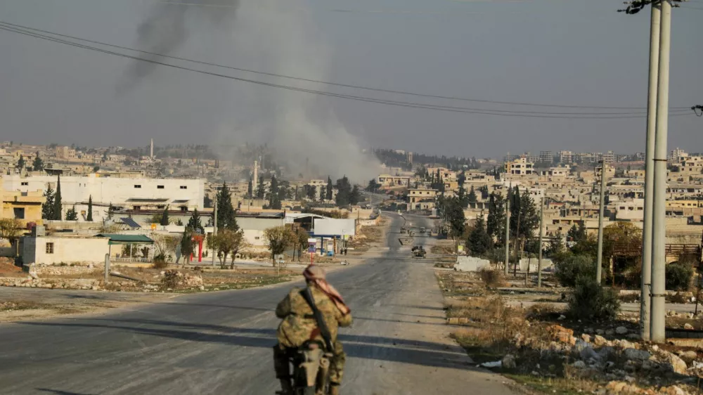 Smoke rises as a member of the rebels led by the Islamist militant group Hayat Tahrir al-Sham drives on a motorbike in al-Rashideen, Aleppo province, Syria November 29, 2024. REUTERS/Mahmoud Hasano