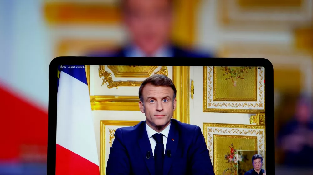 French President Emmanuel Macron appears on screen as he makes a television address to the nation after Prime Minister Michel Barnier's government was toppled in a no confidence vote in parliament, in Paris, France, December 5, 2024. REUTERS/Christian Hartmann