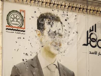 An image of Syrian President Bashar Assad, riddled with bullets, is seen on the facade of the provincial government office in the aftermath of the opposition's takeover of Hama, Syria, Friday, Dec. 6, 2024. (AP Photo/Omar Albam)