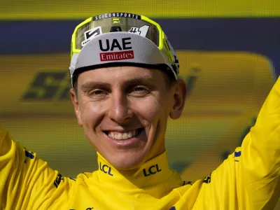 Slovenia's Tadej Pogacar, wearing the overall leader's yellow jersey, celebrates on the podium after the twentieth stage of the Tour de France cycling race over 132.8 kilometers (82.5 miles) with start in Nice and finish in La Couillole pass, France, Saturday, July 20, 2024. (AP Photo/Jerome Delay)