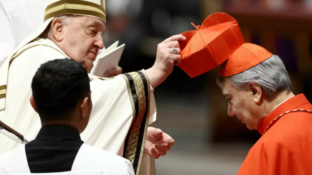 Pope Francis places the traditional red biretta, a four-cornered hat, on the head of new Cardinal Domenico Battaglia during a consistory ceremony to elevate Roman Catholic prelates to the rank of cardinal, in Saint Peter's Basilica at the Vatican, December 7, 2024. REUTERS/Guglielmo Mangiapane