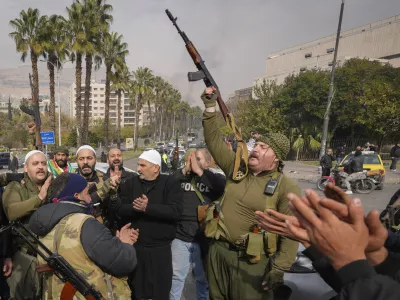 Opposition fighters celebrate the take over of the city by the insurgents in Damascus, Syria, Sunday Dec. 8, 2024. (AP Photo/Hussein Malla)