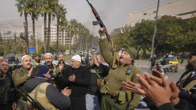 Opposition fighters celebrate the take over of the city by the insurgents in Damascus, Syria, Sunday Dec. 8, 2024. (AP Photo/Hussein Malla)