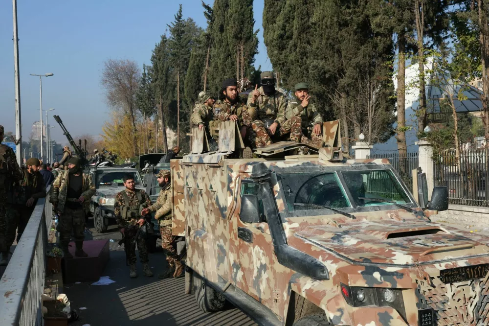 Rebel fighters sit on a vehicle, after rebels seized the capital and ousted President Bashar al-Assad, in Damascus, Syria, December 9, 2024. REUTERS/Mohamed Azakir