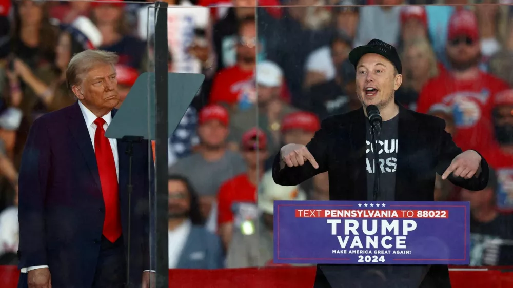 FILE PHOTO: Tesla CEO and X owner Elon Musk speaks as Republican presidential nominee and former U.S. president Donald Trump looks on during a rally at the site of the July assassination attempt against Trump, in Butler, Pennsylvania, U.S., October 5, 2024. REUTERS/Carlos Barria/File Photo