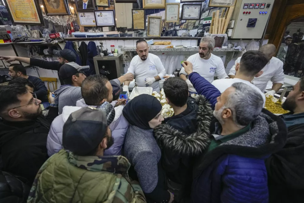 Syrians buy prepared food at the Al-Hamidiyeh market inside the old walled city of Damascus, Syria, Tuesday, Dec. 10, 2024. (AP Photo/Hussein Malla)