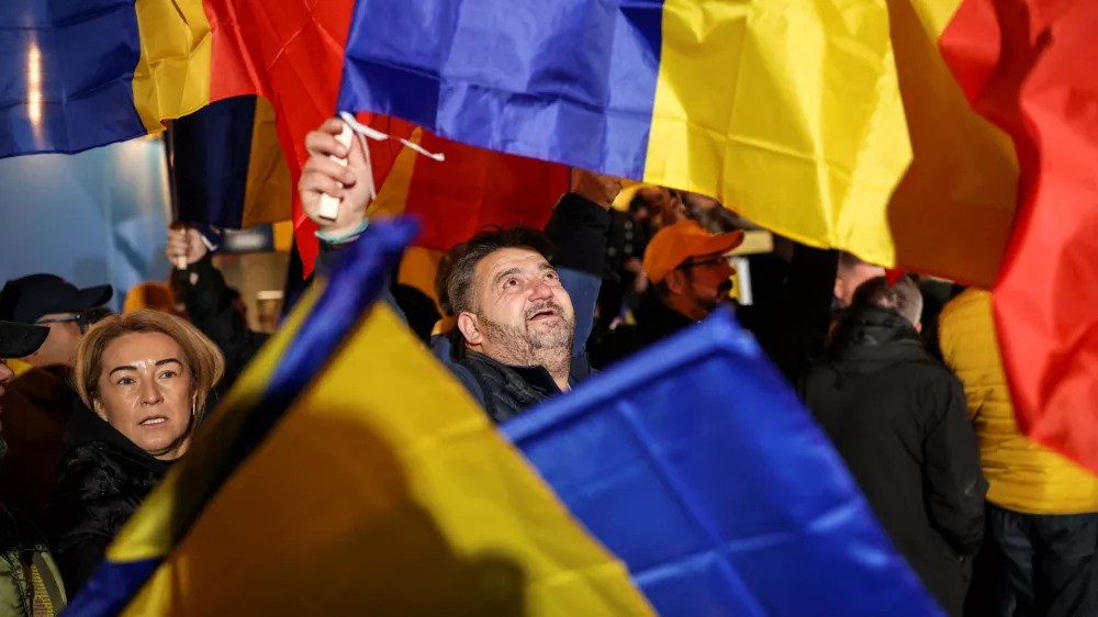 FILE PHOTO: A supporter of the radical right Alliance for Uniting Romanians (AUR) wave a Romanian flag, following the first exit polls, at the party's campaign headquarters, on the day of the parliamentary election, in Bucharest, Romania, December 1, 2024. REUTERS/Alkis Konstantinidis/File Photo