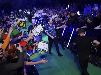 Luke Humphries, center, walks out ahead of his third-round match against Nick Kenny on the 10th day of the Paddy Power World Darts Championship at Alexandra Palace, London, England, Friday, Dec. 27, 2024. (Bradley Collyer/PA via AP)