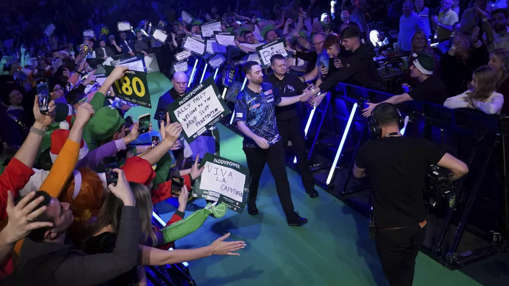 Luke Humphries, center, walks out ahead of his third-round match against Nick Kenny on the 10th day of the Paddy Power World Darts Championship at Alexandra Palace, London, England, Friday, Dec. 27, 2024. (Bradley Collyer/PA via AP)