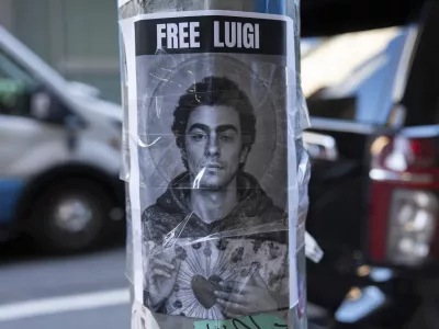 A poster depicting Luigi Mangione hangs outside the New York Hilton Midtown hotel, in New York, Dec. 12, 2024. (AP Photo/Julia Demaree Nikhinson)