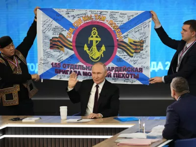 Men hold a replica of the banner of the 155th Marine Brigade of the Pacific Fleet, participating in a special military operation in Ukraine during Russian President Vladimir Putin's annual news conference and call-in show at Gostinny Dvor in Moscow, Russia, Thursday, Dec. 19, 2024. (AP Photo/Alexander Zemlianichenko)