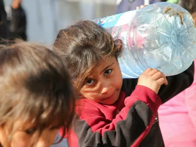 A Palestinian child carries a water container, as Palestinians wait to collect water following a Human Rights Watch report that says Israel's deprivation of water in Gaza is an act of genocide, amid the ongoing conflict between Israel and Hamas, in Khan Younis in the southern Gaza Strip December 19, 2024. REUTERS/Hatem Khaled    TPX IMAGES OF THE DAY