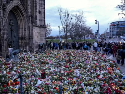 People lay flowers and lit candles in front of the Johannis church close to the Christmas market, where a car drove into a crowd on Friday evening, in Magdeburg, Germany, Sunday, Dec. 22, 2024. (AP Photo/Ebrahim Noroozi)