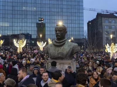 People gather around the bust of Dimitrije Tucovic, early 20th century Serbian socialist politician, during a protest against populist President Aleksandar Vucic and his government, in central Belgrade, Serbia, Sunday, Dec. 22, 2024. (AP Photo/Marko Drobnjakovic)