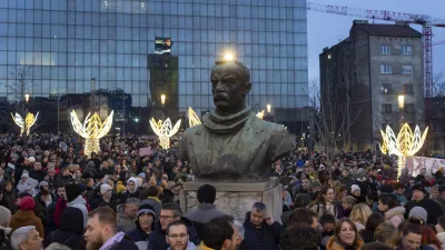 People gather around the bust of Dimitrije Tucovic, early 20th century Serbian socialist politician, during a protest against populist President Aleksandar Vucic and his government, in central Belgrade, Serbia, Sunday, Dec. 22, 2024. (AP Photo/Marko Drobnjakovic)