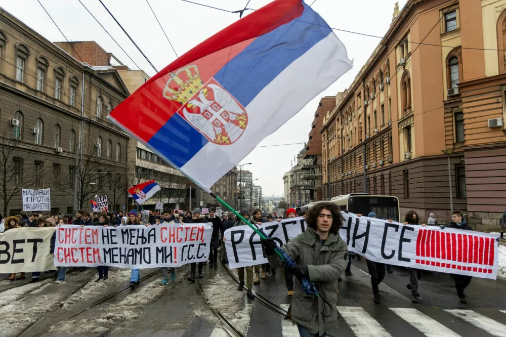 A student waves a flag, as others hold banners and chant slogans during a protest, demanding action from the state prosecutor in the case of the deaths of the victims in the Novi Sad railway station disaster in November, in Belgrade, Serbia, December 25, 2024. REUTERS/Djordje Kojadinovic