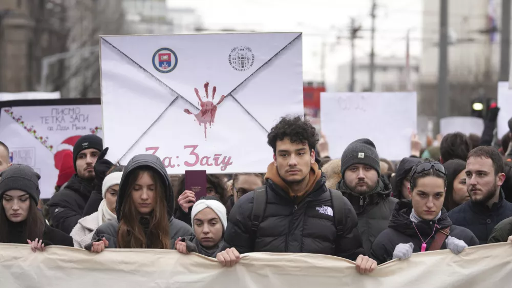 People stopping traffic, stand in silence during ongoing protests that erupted after a concrete canopy fell last month and killed 15 people in front of the government building in Belgrade, Serbia, Wednesday, Dec. 25, 2024. (AP Photo/Darko Vojinovic)