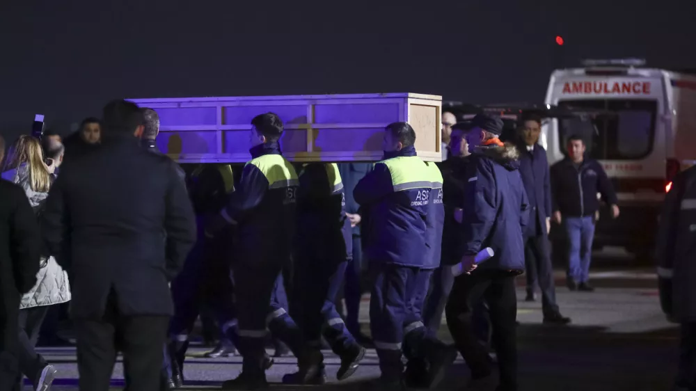 Workers carry a coffin with a body of a victim from a medical plane after the Azerbaijani Airline crashed, near the Kazakhstani city of Aktau, upon their arrival at the Heydar Aliyev International Airport outside Baku, Azerbaijan, Thursday, Dec. 26, 2024. (AP Photo)