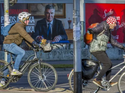 Cyclists ride past a poster of incumbent President Zoran Milanovic ahead of the presidential election in Zagreb, Croatia, Thursday, Dec. 26, 2024. (AP Photo)