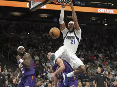 Dallas Mavericks center Daniel Gafford dunks over Phoenix Suns forward Ryan Dunn (0) and center Mason Plumlee during the second half of an NBA basketball game, Friday, Dec. 27, 2024, in Phoenix. Dallas won 98-89. (AP Photo/Rick Scuteri)